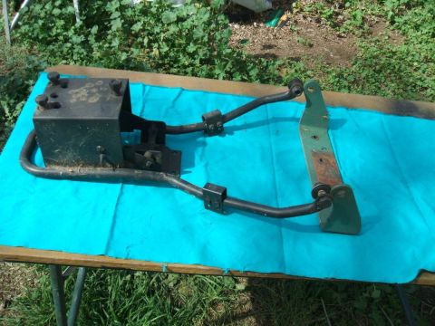 1991 Ford Bronco - Automotive part with linkages and bracket, displayed on a table outdoors.