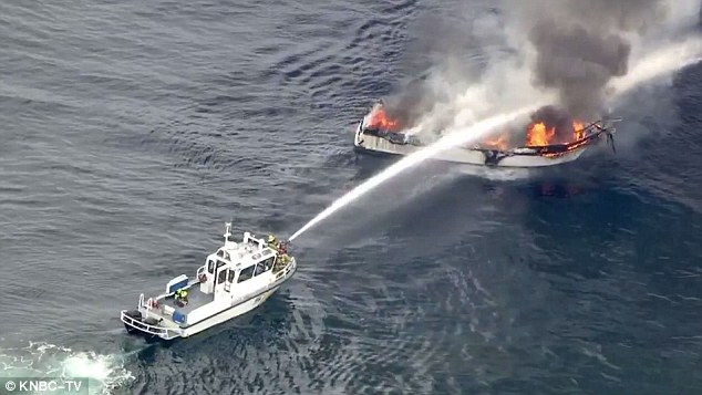 Boat spraying water on another boat that is on fire