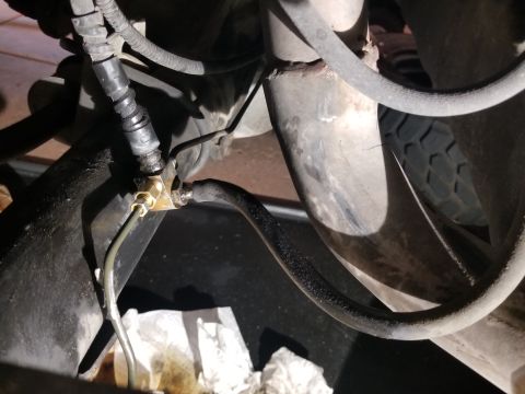 1993 Ford Bronco - A close-up view of a vehicle's brake line connection, showing some fluid residue.