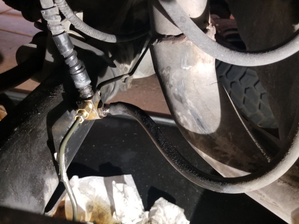 close-up of a vehicle's brake line connection with some fluid drips