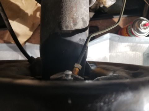 1993 Ford Bronco - Close-up view of a brake line connected to a drum brake assembly, likely from a vehicle undergoing maintenance.