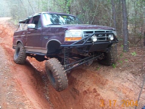 1986 Ford Bronco - This modified 1992 Ford Bronco tackles a challenging off-road trail with its lifted suspension and aggressive tires.