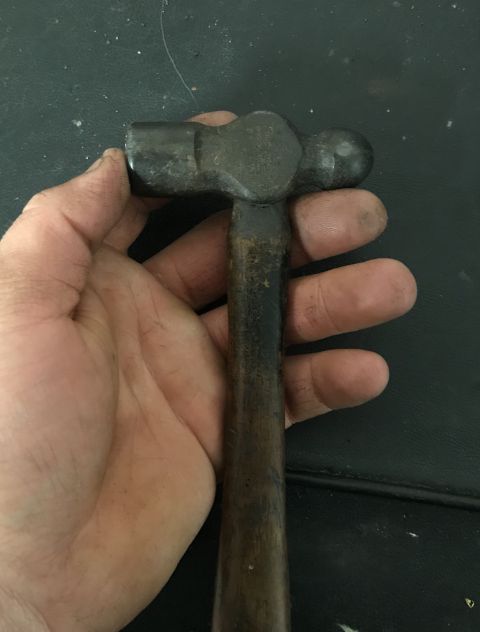 1995 Ford Bronco - A ball-peen hammer is held up, revealing its worn metal head and wooden handle.
