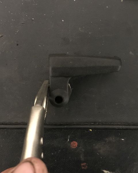 1995 Ford Bronco - A black plastic component is being gripped by pliers on a textured surface, with a website logo in the corner.