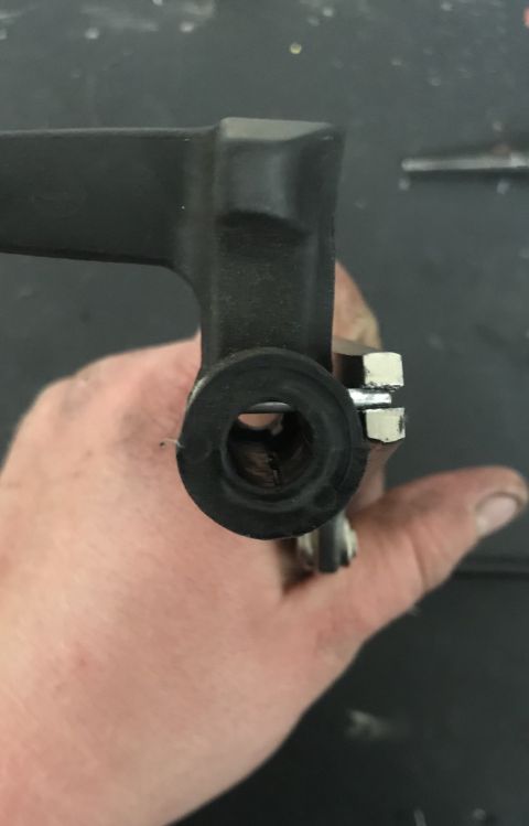 1995 Ford Bronco - A close-up view of a metal bracket with a rubber bushing, held by a hand.