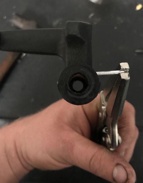 1995 Ford Bronco - Close-up of a hand holding a part with pliers, with a metal pin engaged.