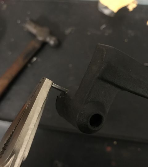 1995 Ford Bronco - A close-up view of a black metal part being worked on with pliers and a hammer nearby hammer.
