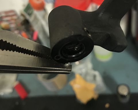 1995 Ford Bronco - A close-up shows pliers holding a black component, possibly a car part, with a visible circular opening.