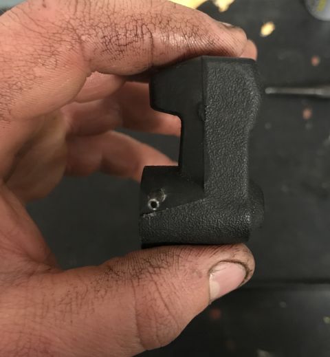 1995 Ford Bronco - A hand holds a black plastic part, possibly a trim piece, with a small metal pin visible.