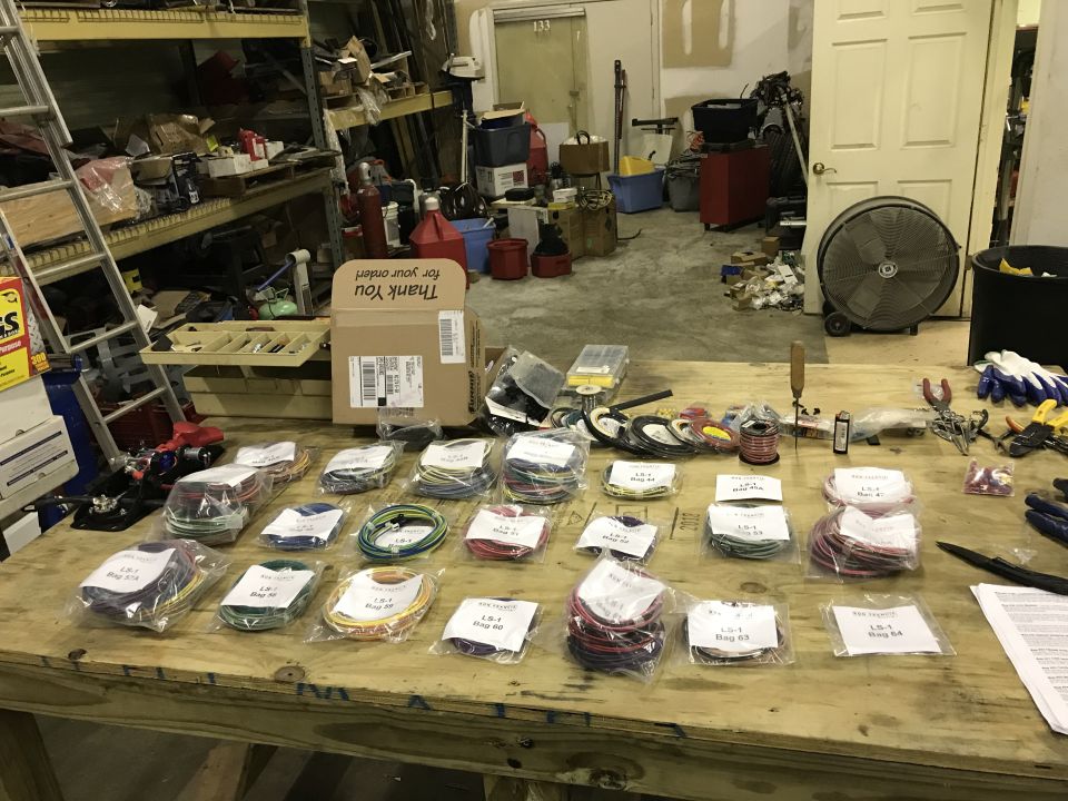 Table with many bags of colored electrical wire kits, tools like pliers and screwdrivers, and a 'Thank You for your order' box