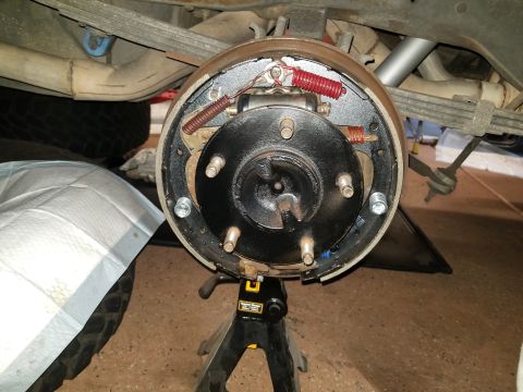 1993 Ford Bronco - Close-up of a vehicle's rear drum brake assembly, supported by jack stands.
