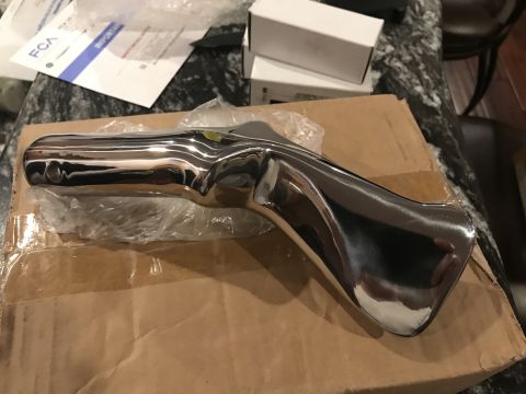 1923 Ford Model T - A shiny chrome bumper part is shown resting on a cardboard box, with some paperwork visible in the background.