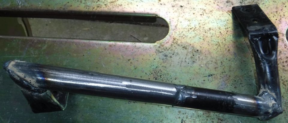 metal bracket welded to a rod, with another metal piece above