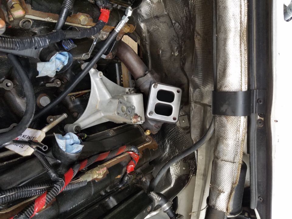 Engine bay showing turbocharger exhaust housing and plumbing. Some blue rags are stuffed into openings