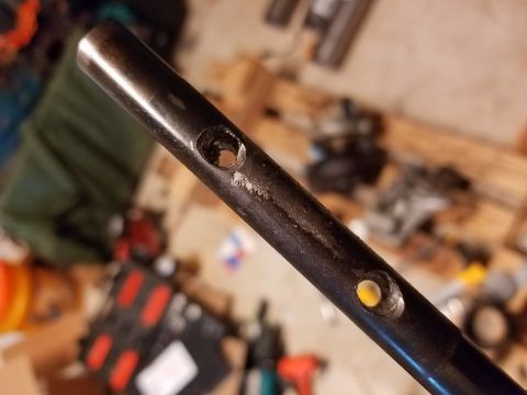 1995 Ford F-250 - A metal rod with two holes is shown in detail, with a blurred background of tools and parts.