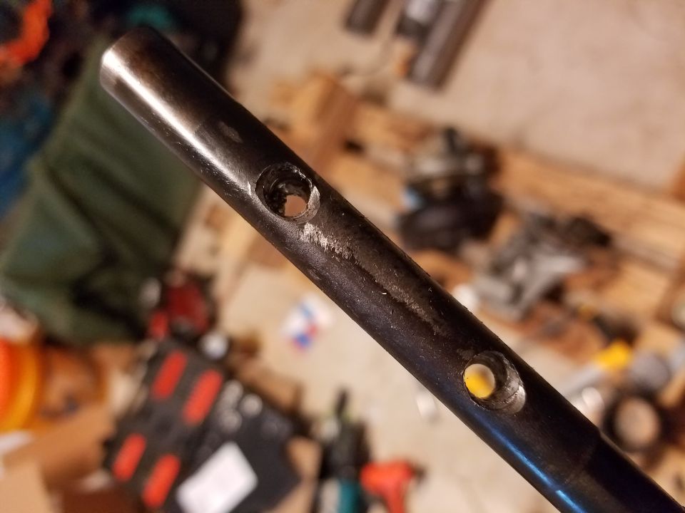 Close-up of a dark metal rod with two holes drilled into it