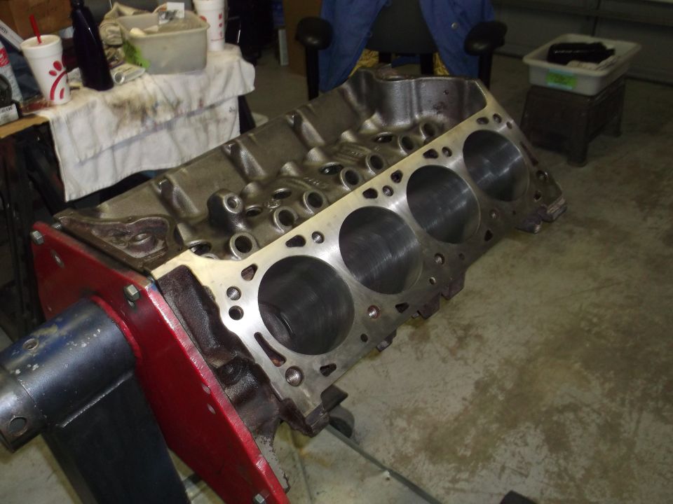 Engine block on a red stand, showing cylinder bores and bolt holes
