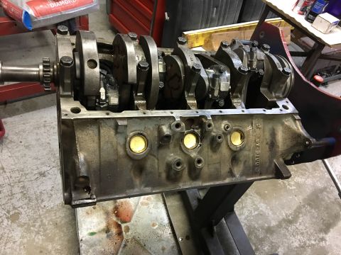1976 Ford Ranchero - Engine block with crankshaft and connecting rods is shown on a stand in a workshop.