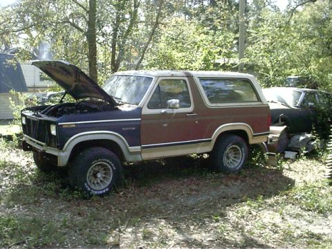 1985 Ford Bronco - This 1985 Ford Bronco, seen from a 3q-front angle, has its hood open and appears to be in a yard with another vehicle in the background.