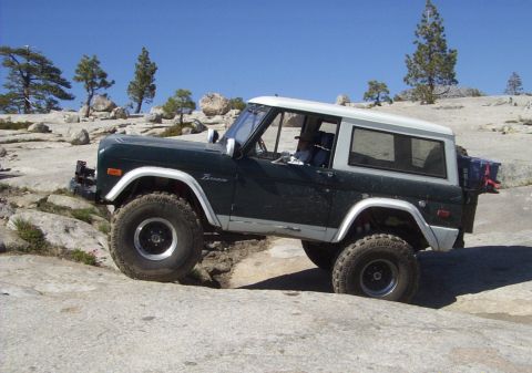 1984 Ford Bronco - Ford Bronco tackles a challenging rocky trail under a clear blue sky.