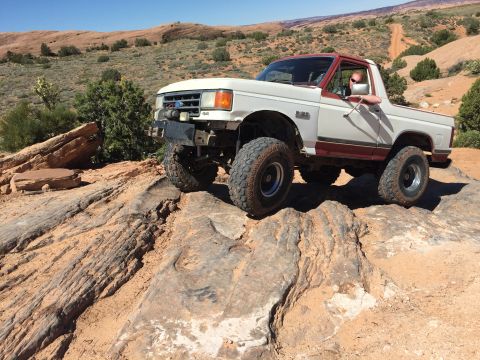 1984 Ford Bronco - This 1987 Ford Bronco navigates a challenging rocky trail under a clear blue sky.