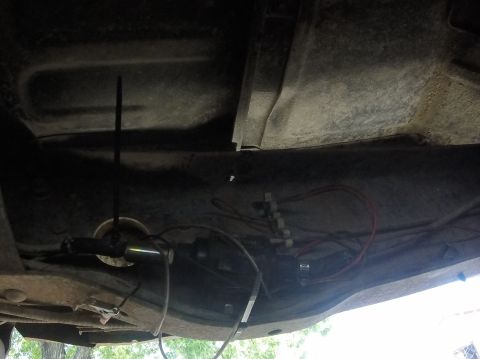1984 Ford Bronco - The underside of a vehicle reveals its fuel lines and wiring, with a watermark indicating the source.