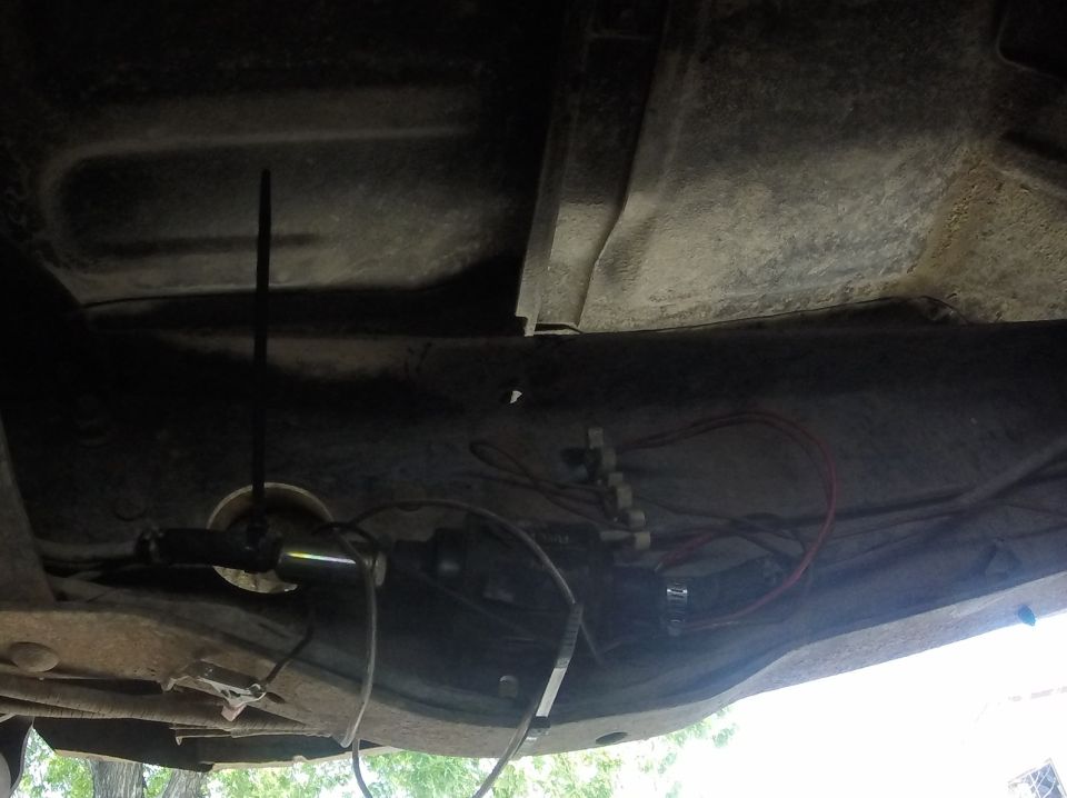 Underside of a vehicle showing fuel lines and wiring harness, with a Supermotors.net watermark