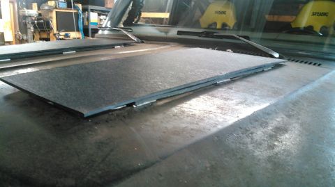 1978 Ford Bronco - Two black mats are placed on the hood of a vehicle in a workshop.