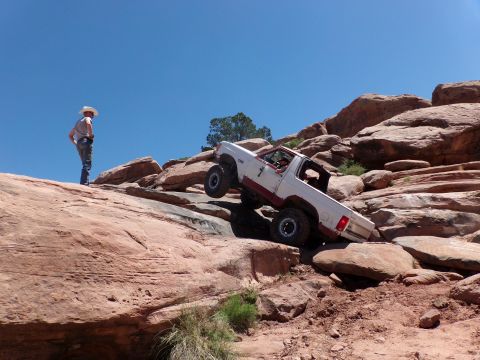 1984 Ford Bronco - Off-road SUV navigates challenging rocky terrain on a sunny day.