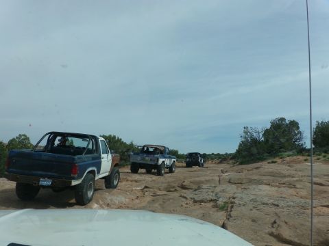 1984 Ford Bronco - Multiple off-road vehicles navigate a challenging rocky terrain on a trail.