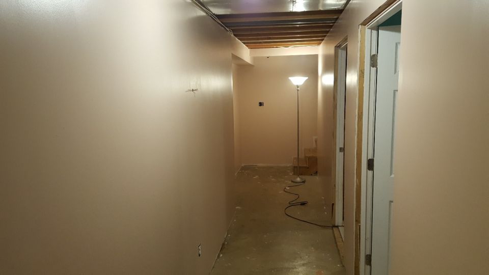 Interior hallway with bare concrete floor, unfinished ceiling, and a floor lamp