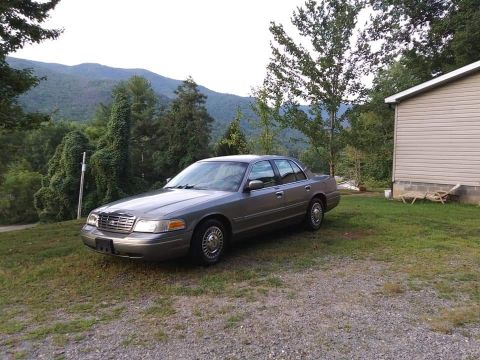 2000 Ford Crown Victoria - A 2000 Ford Crown Victoria is parked outside a rural home with a mountainous landscape behind it.