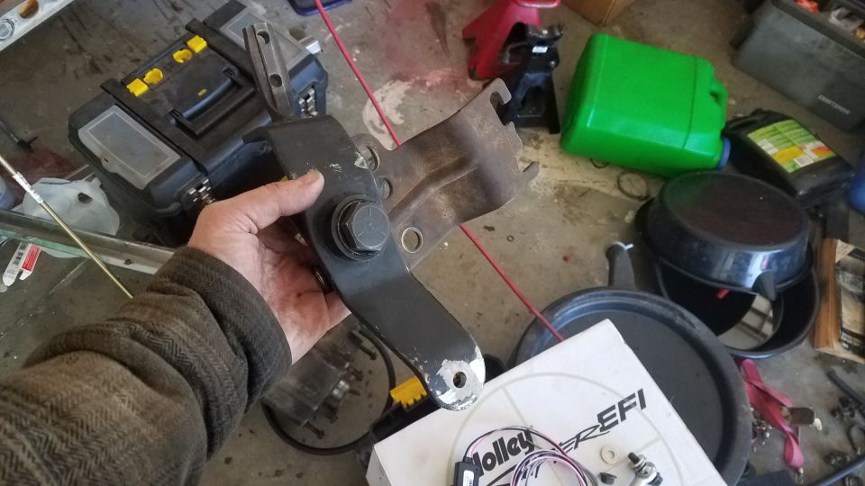 Metal bracket held in hand, with "SUPERMOTORS" text visible on a box below