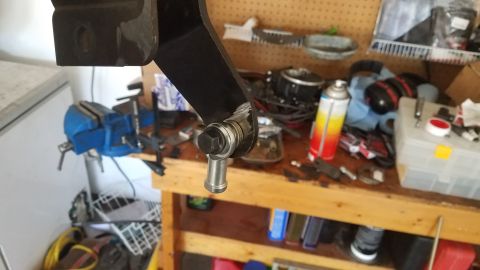1985 Ford Bronco - A close-up view of an automotive part, likely a suspension component, on a cluttered workbench.