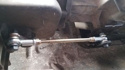 1985 Ford Bronco - Close-up view of an aftermarket shifter linkage installed on a vehicle's transmission.
