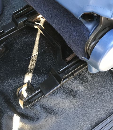1995 Ford Bronco - Close-up of a vehicle's interior seat mounting hardware and blue fabric.