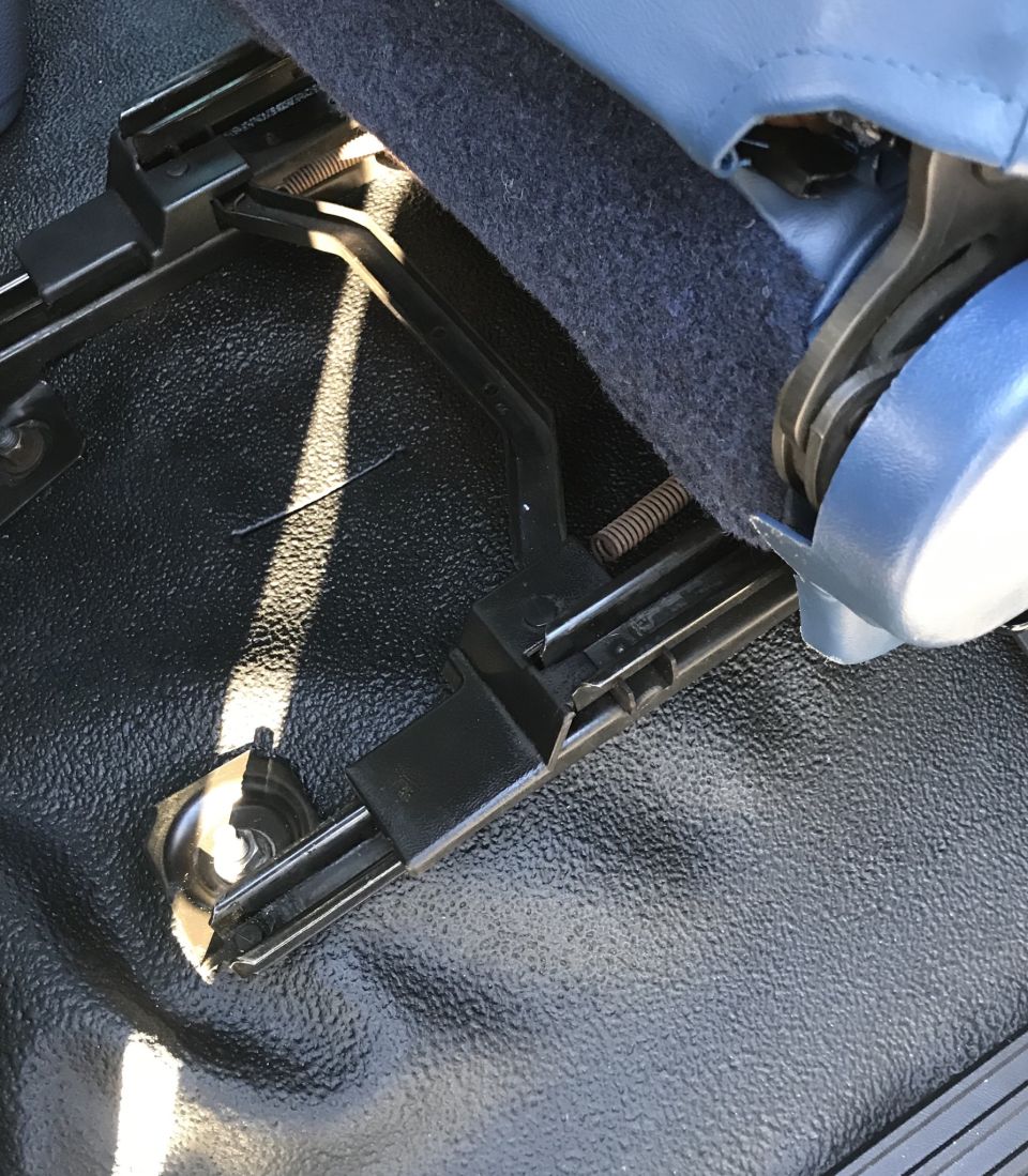 Seat mounting bracket and blue upholstery on textured floor