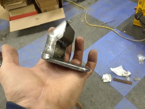 1985 Ford Bronco - A metal bracket is held in a hand, with a box and tools in the background.