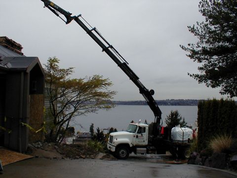 1983 Ford Bronco - A crane truck is positioned near a building site with a body of water in the distance.