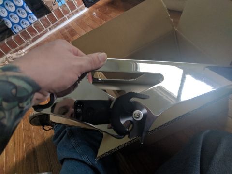 2014 Harley-Davidson FXDWGI Wide Glide - Shiny chrome motorcycle part being unboxed, likely a new accessory or replacement component.