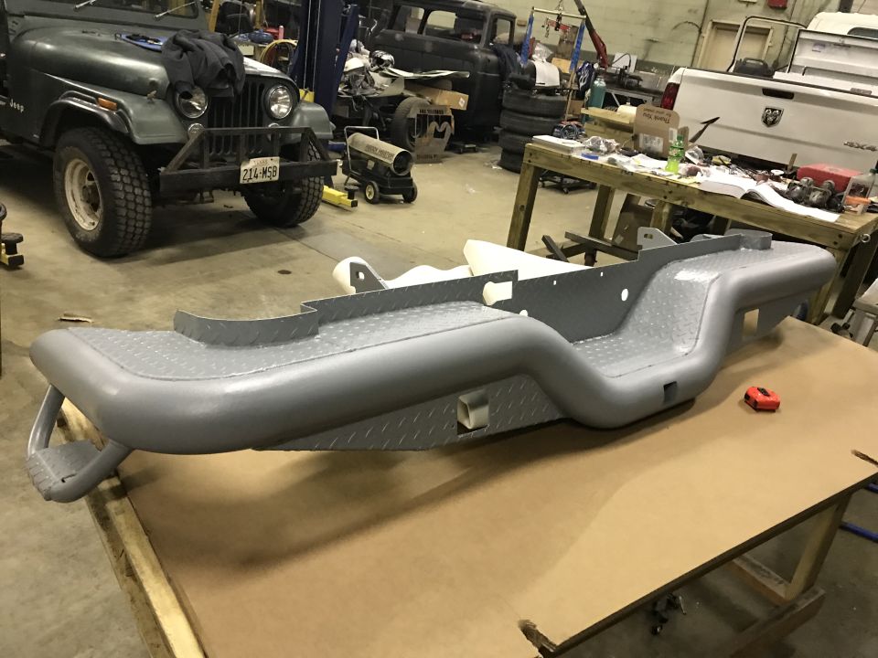 Truck rear bumper on a table, jeep and other vehicles in background