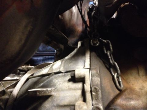 1978 Ford Bronco - Close-up view of an engine transmission assembly being worked on, with a chain hoist attached.
