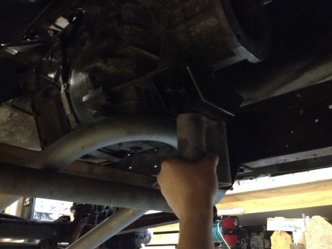 1978 Ford Bronco - Working on the undercarriage of a vehicle, focusing on a pipe and bracket assembly.