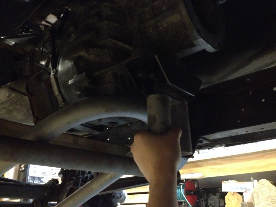 Hand holding a pipe against the underbody of a vehicle