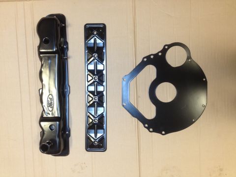 1978 Ford Bronco - Black Ford valve cover, intake manifold, and timing cover gasket laid out on a cardboard surface.