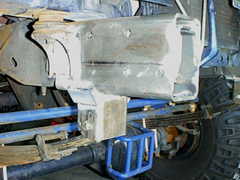 1995 Ford Bronco - The underside of a vehicle shows custom metalwork and suspension components, including leaf springs and blue-painted bars.