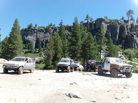 1984 Ford Bronco - Off-road vehicles gathered in a scenic, mountainous landscape under a clear blue sky.