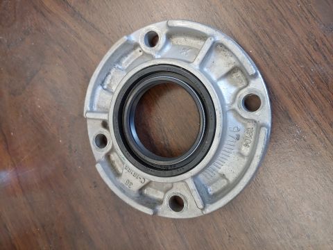 1995 Ford Bronco - A close-up view of a metal part with a black seal, resting on a wooden table.