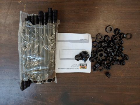 1995 Ford Bronco - Engine studs, washers, and caps are laid out with instructions on a wooden surface.