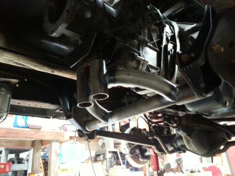 1978 Ford Bronco - The underside of a vehicle shows a custom exhaust system being installed, with dual pipes emerging from a Y-pipe and connecting to a muffle…